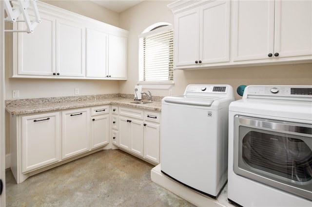 clothes washing area with cabinet space, washing machine and dryer, and a sink