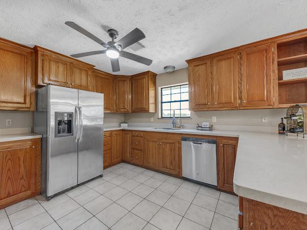 kitchen featuring appliances with stainless steel finishes, a textured ceiling, light tile patterned floors, and ceiling fan