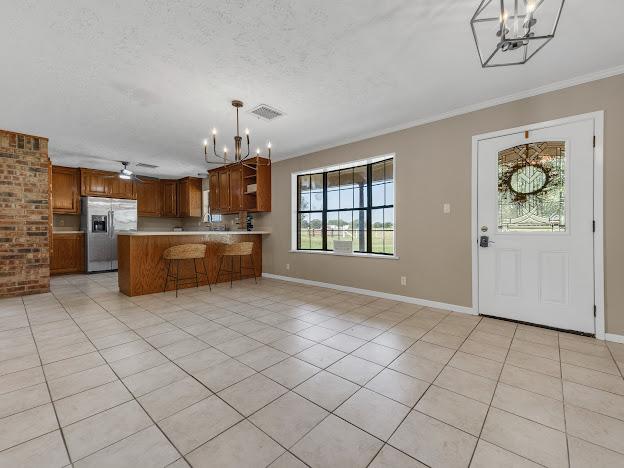 kitchen featuring stainless steel fridge, decorative light fixtures, light tile patterned floors, and a wealth of natural light