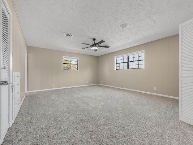 unfurnished bedroom with ceiling fan, light colored carpet, and a textured ceiling