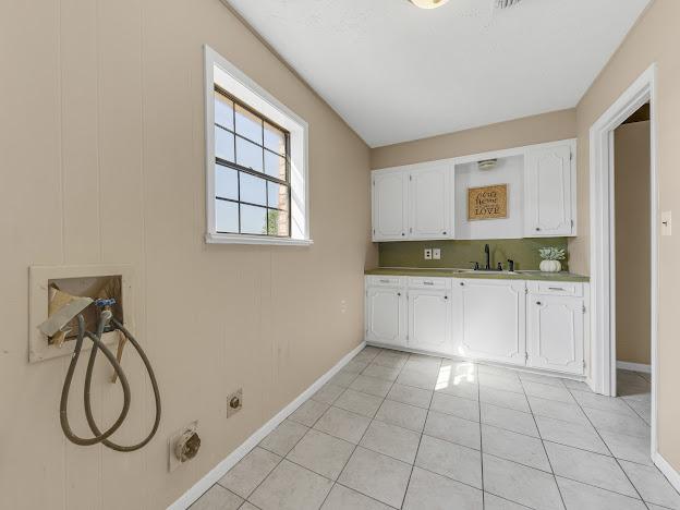 washroom with sink, light tile patterned flooring, and cabinets