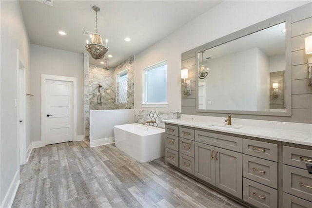 bathroom featuring vanity, tile walls, plus walk in shower, hardwood / wood-style floors, and a chandelier