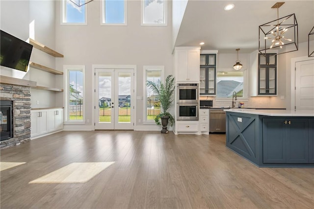 kitchen featuring hanging light fixtures, dark hardwood / wood-style floors, a fireplace, white cabinetry, and stainless steel appliances