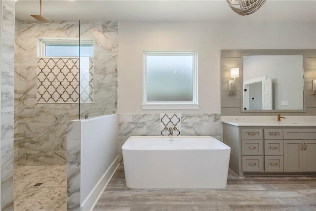 bathroom with plus walk in shower, vanity, hardwood / wood-style flooring, and tile walls