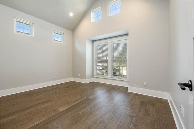 spare room featuring plenty of natural light, high vaulted ceiling, and dark wood-type flooring