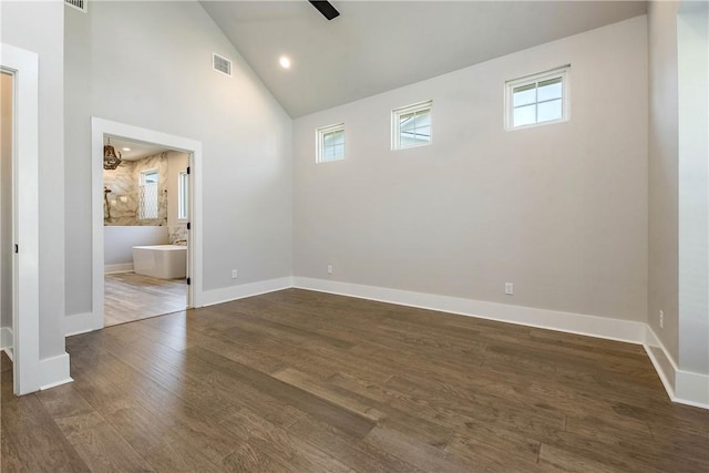 empty room featuring dark hardwood / wood-style floors, high vaulted ceiling, and a wealth of natural light