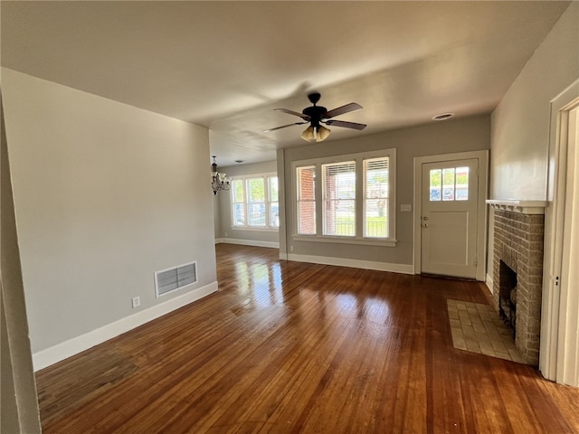 unfurnished living room with baseboards, visible vents, a fireplace, and dark wood-type flooring