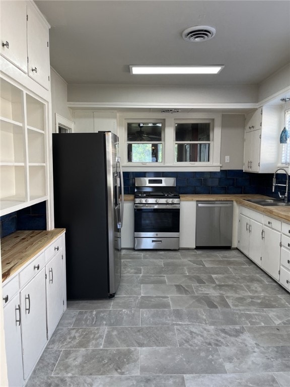 kitchen with a sink, visible vents, white cabinetry, decorative backsplash, and appliances with stainless steel finishes