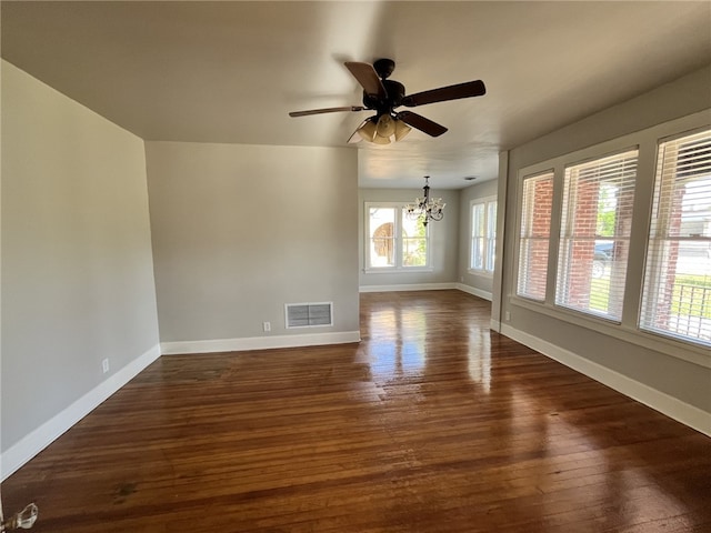 unfurnished room featuring visible vents, baseboards, dark wood-style flooring, and ceiling fan with notable chandelier