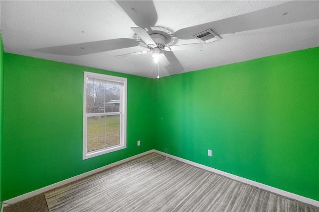 carpeted empty room with ceiling fan and a textured ceiling