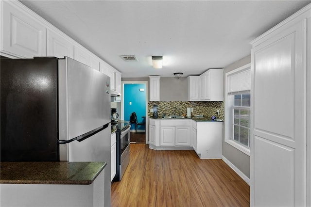 kitchen featuring tasteful backsplash, light wood-type flooring, white cabinets, and appliances with stainless steel finishes