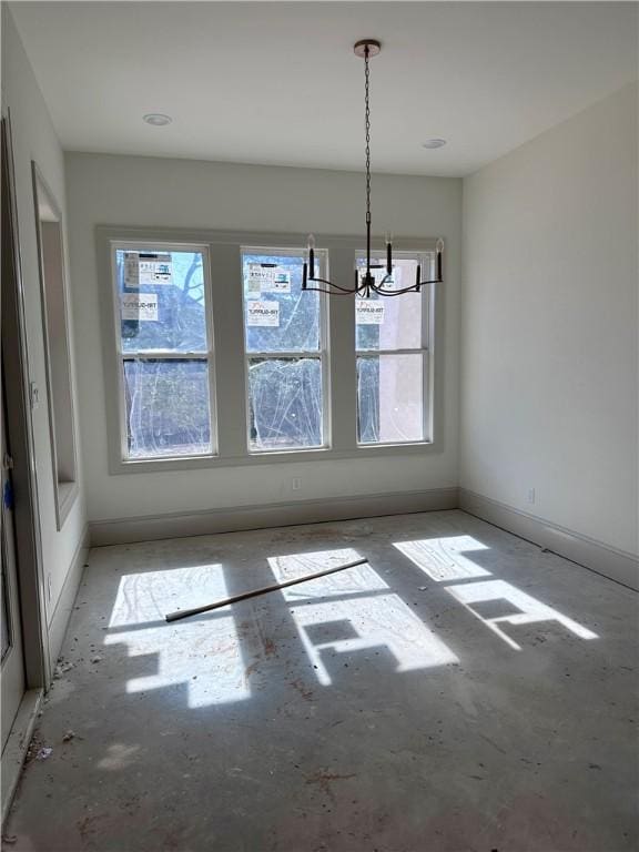 unfurnished dining area with baseboards and a chandelier