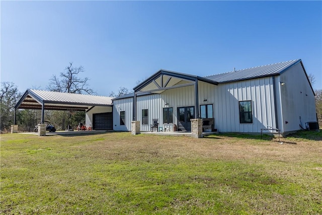 rear view of house featuring a garage, a lawn, and central air condition unit