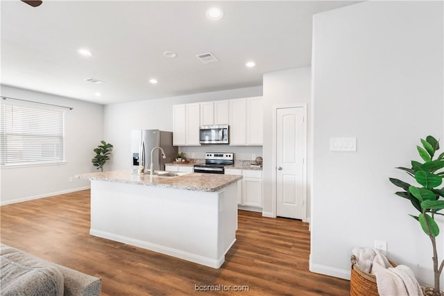 kitchen with dark hardwood / wood-style floors, white cabinetry, a kitchen island with sink, and appliances with stainless steel finishes