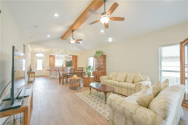 living room with lofted ceiling with beams, ceiling fan, a healthy amount of sunlight, and light wood-type flooring