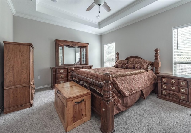 carpeted bedroom with ceiling fan, ornamental molding, and a tray ceiling