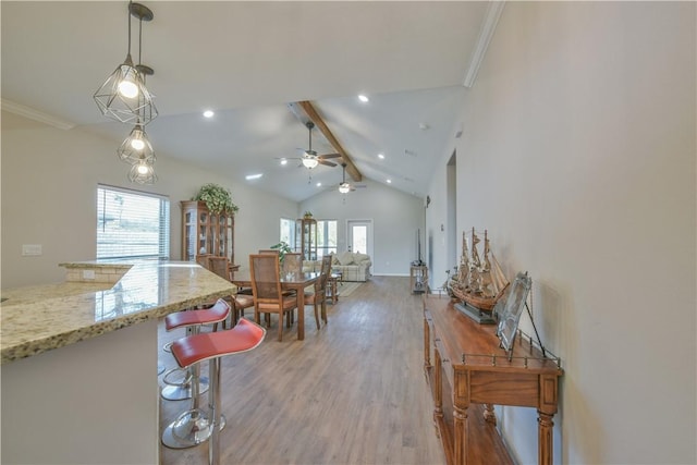 kitchen featuring lofted ceiling with beams, hanging light fixtures, hardwood / wood-style flooring, ceiling fan, and light stone countertops