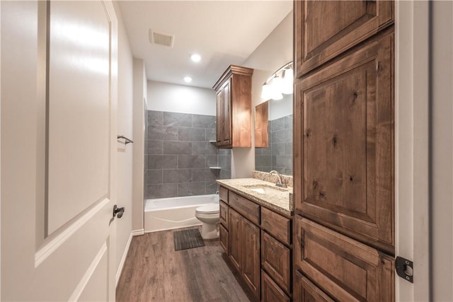 full bathroom featuring tiled shower / bath, toilet, vanity, and hardwood / wood-style flooring