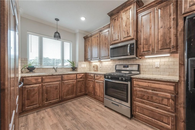 kitchen with crown molding, sink, light wood-type flooring, appliances with stainless steel finishes, and light stone counters