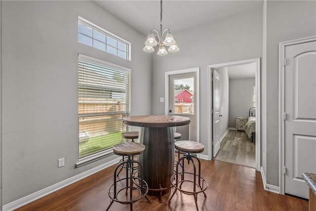 dining area with a notable chandelier and dark hardwood / wood-style flooring