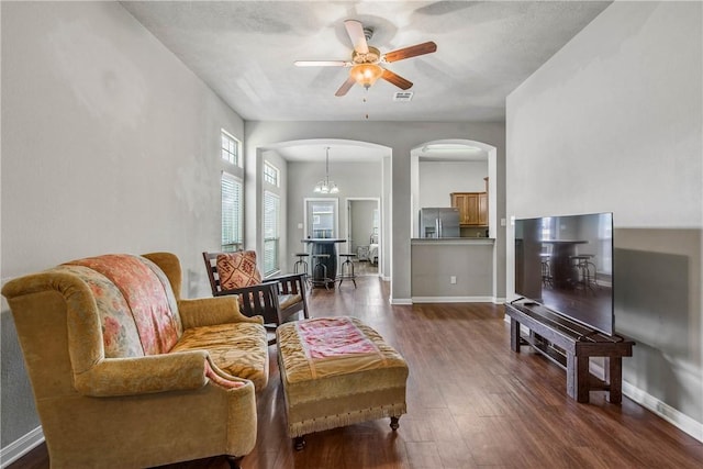 living room featuring ceiling fan with notable chandelier and dark hardwood / wood-style floors