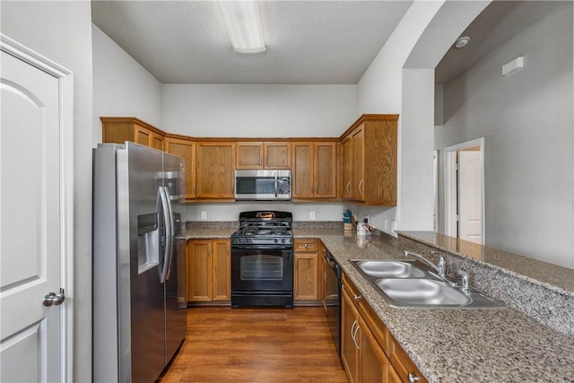 kitchen featuring black appliances, dark hardwood / wood-style flooring, sink, and dark stone counters