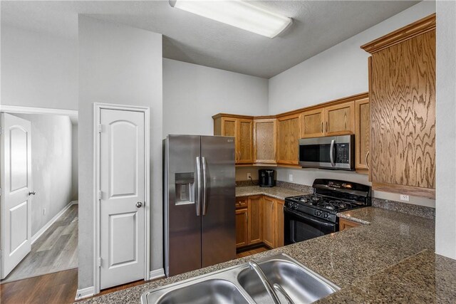 kitchen with sink, kitchen peninsula, stainless steel appliances, and light hardwood / wood-style flooring