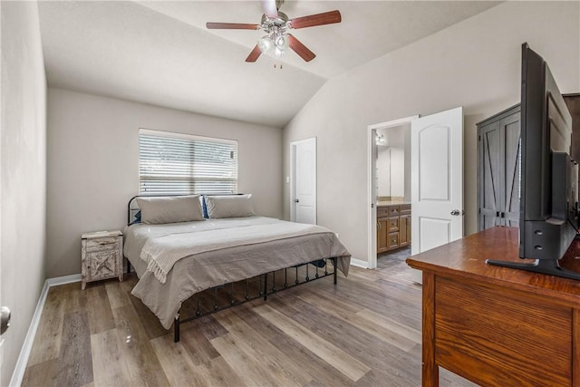 bedroom with ceiling fan, ensuite bathroom, light hardwood / wood-style floors, and vaulted ceiling