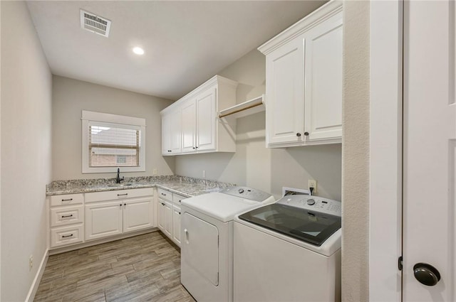 laundry room featuring separate washer and dryer, light hardwood / wood-style flooring, cabinets, and sink