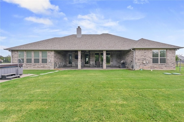 back of property featuring a yard, a hot tub, and a patio area