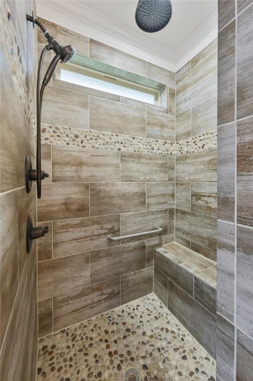 bathroom featuring a tile shower and crown molding