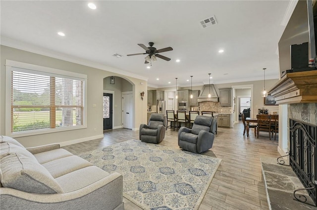 living room with light hardwood / wood-style floors, ceiling fan, and ornamental molding