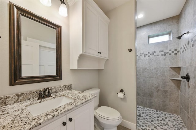 bathroom featuring tiled shower, vanity, and toilet