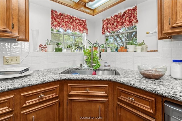 kitchen featuring backsplash, light stone counters, plenty of natural light, and sink