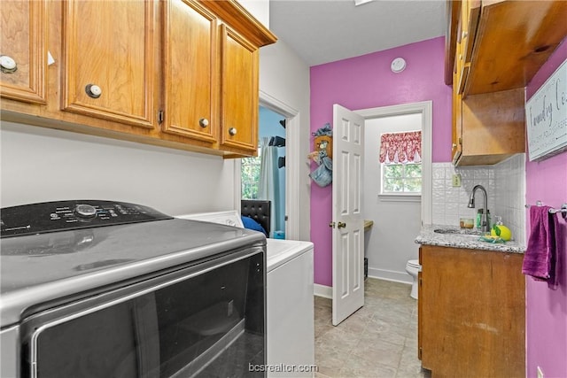 clothes washing area with plenty of natural light, separate washer and dryer, and sink