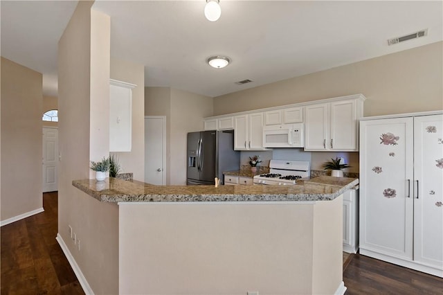 kitchen featuring white appliances, light stone counters, visible vents, and dark wood-style flooring