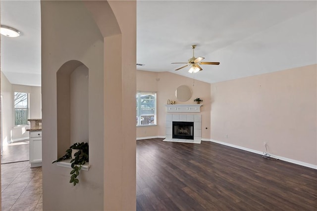 unfurnished living room with a ceiling fan, a healthy amount of sunlight, a fireplace, and vaulted ceiling