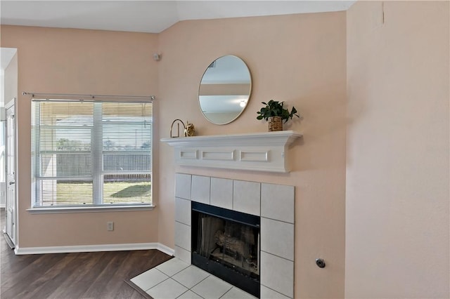 unfurnished living room featuring a fireplace, baseboards, lofted ceiling, and wood finished floors