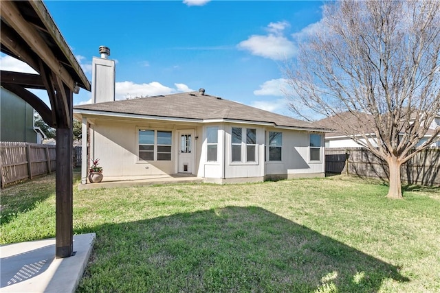 rear view of house featuring stucco siding, a fenced backyard, a lawn, and a chimney