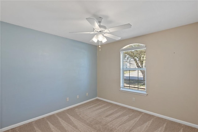 spare room with ceiling fan, baseboards, and light carpet