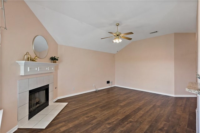 unfurnished living room with wood finished floors, visible vents, lofted ceiling, ceiling fan, and a tile fireplace