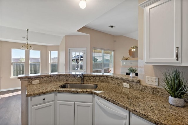 kitchen with pendant lighting, wood finished floors, stone countertops, white dishwasher, and a sink