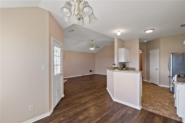 kitchen with dark wood finished floors, freestanding refrigerator, vaulted ceiling, white cabinetry, and ceiling fan with notable chandelier