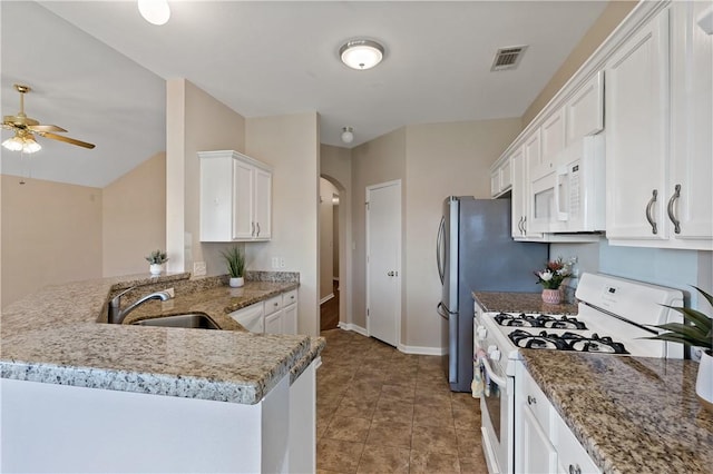 kitchen featuring visible vents, arched walkways, white appliances, white cabinetry, and a sink