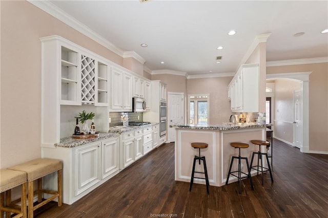 kitchen with white cabinetry, a breakfast bar, stainless steel appliances, and light stone counters