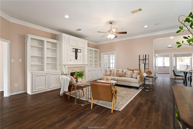 living room with crown molding, ceiling fan, a fireplace, and dark wood-type flooring