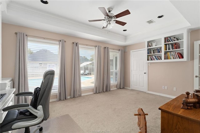 carpeted office with ceiling fan, a raised ceiling, and crown molding