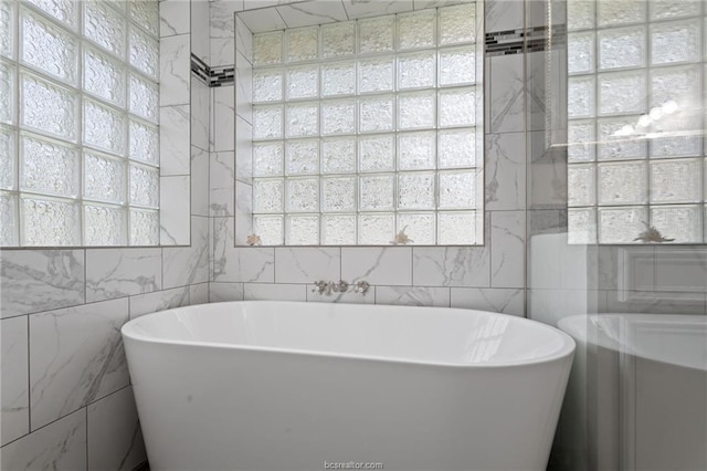 bathroom with a washtub and tile walls