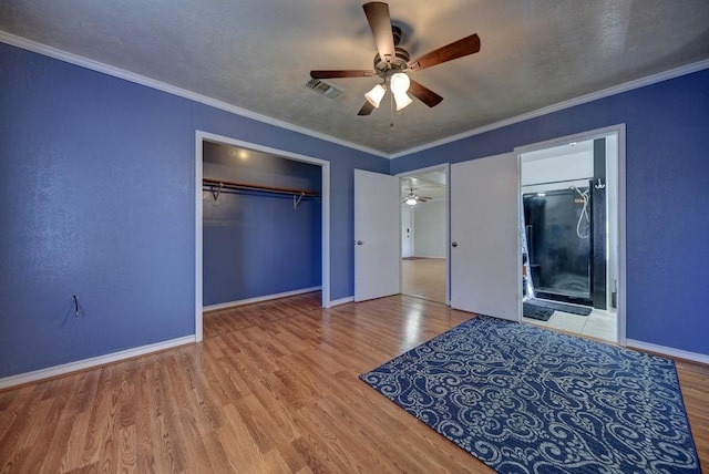 unfurnished bedroom featuring ensuite bathroom, hardwood / wood-style floors, ceiling fan, a closet, and crown molding