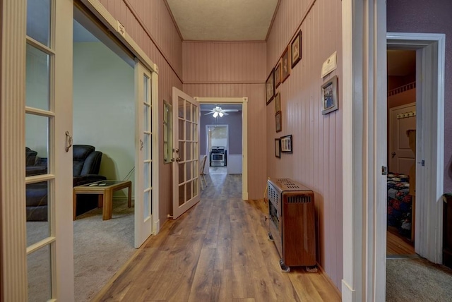 corridor featuring wood-type flooring, ornamental molding, heating unit, and french doors